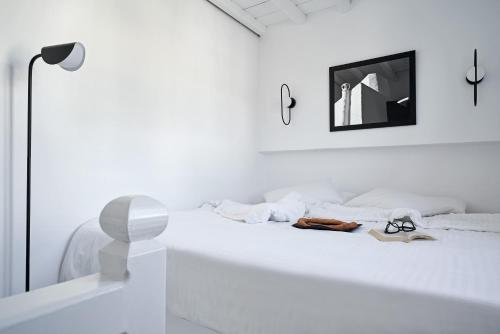 a white bedroom with a white bed with a mirror at Almyra Guest Houses in Paraga