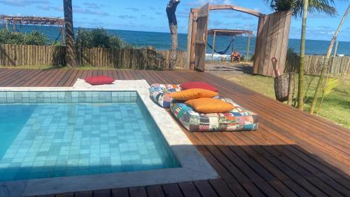 una cama junto a una piscina junto a la playa en Villa do Sossego - Caraíva, en Caraíva