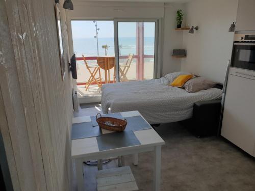 a bedroom with a bed and a table and a balcony at Appartement Front de mer - Vue Ocean in Lacanau-Océan