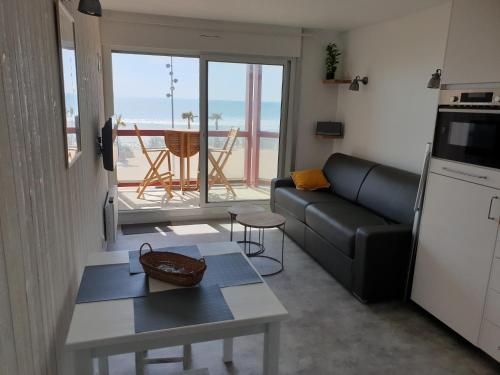 a living room with a couch and a table and a kitchen at Appartement Front de mer - Vue Ocean in Lacanau-Océan