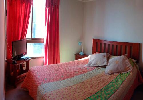 um quarto com uma cama com cortinas vermelhas e uma televisão em Santiago Centro em Santiago