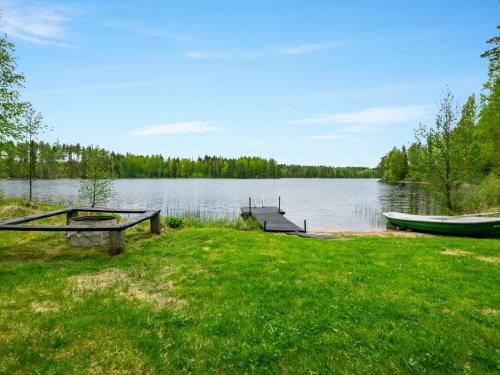 a picnic table and a boat on a lake at Holiday Home Lehtikuusenranta by Interhome in Hankamäki