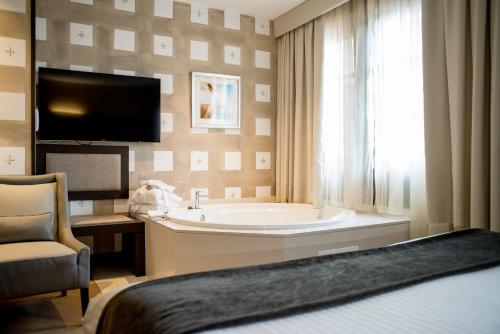 a bathroom with a bath tub and a tv at Costa Esmeralda Suites in Suances
