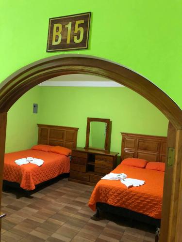 a bedroom with two beds and a sign on the wall at Hotel del Carmen in Retalhuleu