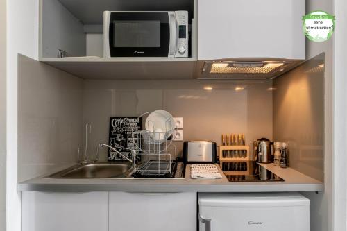 a kitchen with a microwave and a dishwasher at All Suites Bordeaux Marne – Gare Saint-Jean in Bordeaux