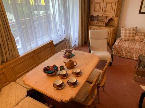 uma sala de estar com uma mesa de madeira com pratos em Cosy apartment in a gorgeous area em Crans-Montana