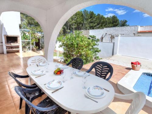 een witte tafel en stoelen op een patio met een zwembad bij Villa Villa Zozo by Interhome in L'Ametlla de Mar