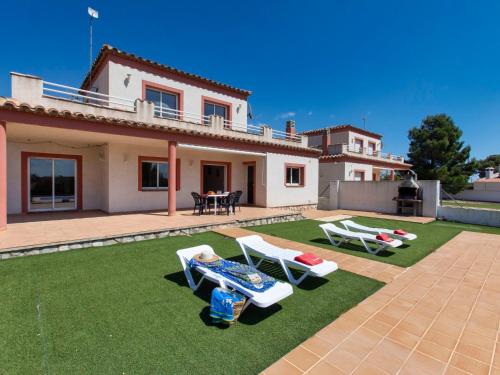 a villa with a yard with lawn chairs and a house at Villa Villa Malva II by Interhome in Les tres Cales