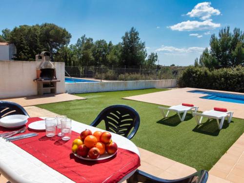 a table with a plate of fruit on top of a yard at Villa Villa Malva II by Interhome in Les tres Cales
