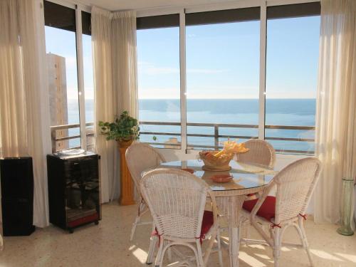 comedor con mesa y sillas frente a las ventanas en Apartment Vistamar by Interhome, en Cala de Finestrat