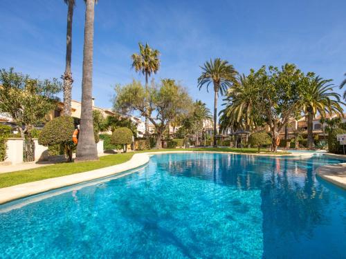 a swimming pool with palm trees in a resort at Holiday Home El Arenal by Interhome in Jávea