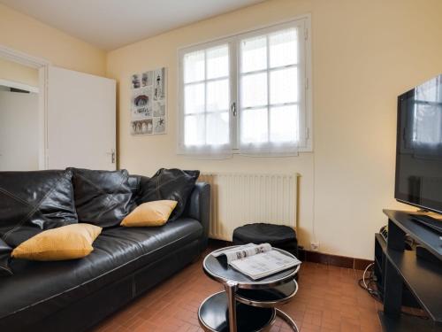 ein Wohnzimmer mit einem schwarzen Ledersofa und einem TV in der Unterkunft Holiday Home Penthievre by Interhome in Légenès