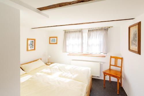 a white bedroom with a bed and a chair at Ferienhaus Behringen in Behringen