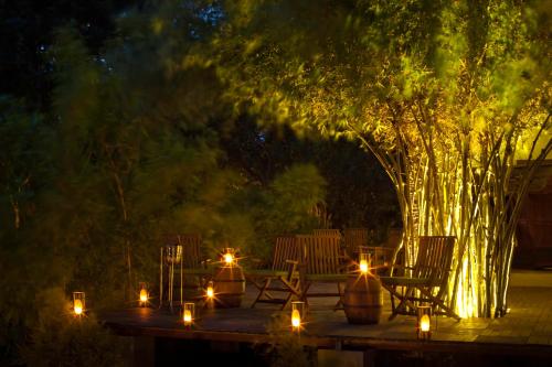 a patio with candles and chairs and a tree at night at The Serai Kabini in Begūr