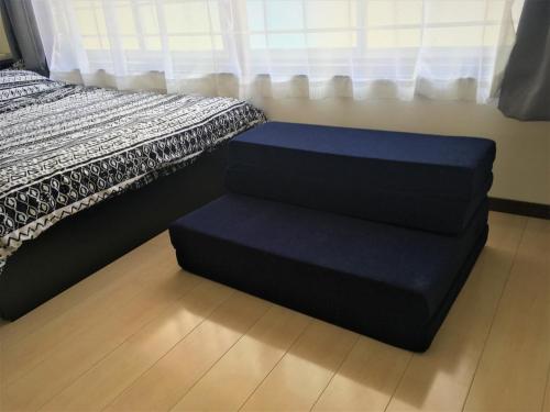 małe łóżko z niebieskim fotelem obok okna w obiekcie 002.Standard Number w mieście Kumamoto