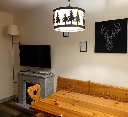a room with a table and a television and a chandelier at Bilocale con vista a Sestriere in Sestriere