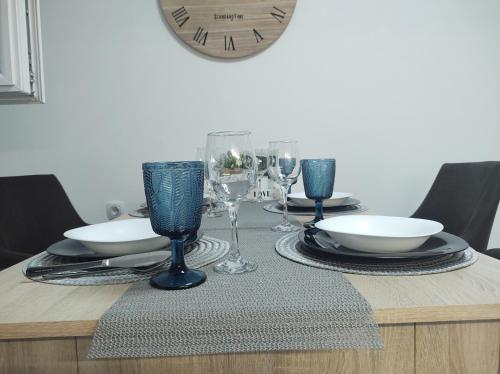 - une table avec des assiettes, des verres à vin et une horloge dans l'établissement Apartment Iskra, aux lacs de Plitvice