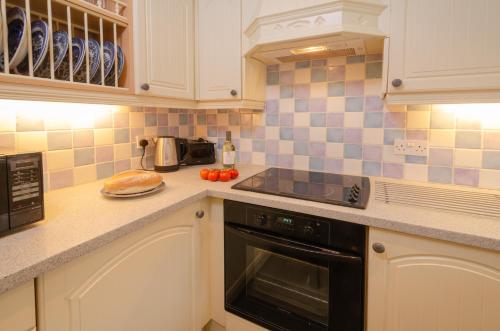 a kitchen with white cabinets and a black stove top oven at 2 Bridge Syke, Elterwater in Chapel Stile