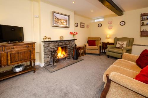 a living room with a fireplace and a tv at 2 Bridge Syke, Elterwater in Chapel Stile