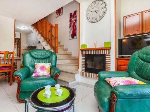ミアミ・プラトーヤにあるHoliday Home Isis by Interhomeのリビングルーム(緑の椅子2脚、暖炉付)