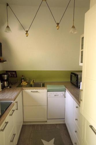 Una cocina con gabinetes blancos y un fregadero. en Ladwig - Ferienhaus Adda, en Südbrookmerland