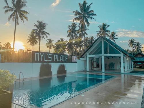 a swimming pool in front of a building with palm trees at Dreamink farm og Myl`s place in Sorsogon