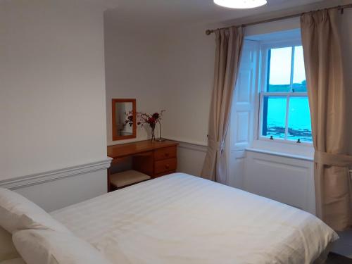 a bedroom with a white bed and a window at Colebrook Cottage in Isle of Whithorn