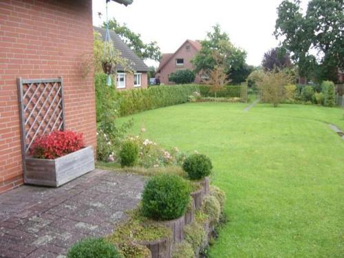 a yard with a brick house and a lawn with flowers at Ferienwohnung Klatto in Südbrookmerland