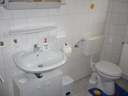 a white bathroom with a sink and a toilet at Ferienwohnung Klatto in Südbrookmerland