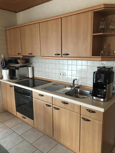 eine Küche mit Holzschränken und einem Waschbecken in der Unterkunft Ferienwohnung Klatto in Südbrookmerland