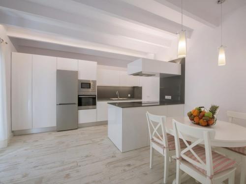 コスティッチにあるHoliday Home Es Reco by Interhomeの白いキャビネット、テーブルと椅子付きのキッチンが備わります。