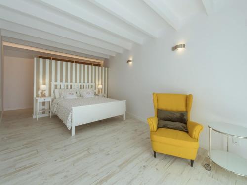 a bedroom with a bed and a yellow chair at Holiday Home Es Reco by Interhome in Costitx