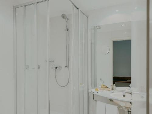 a white bathroom with a shower and a sink at Bad Hotel Überlingen in Überlingen