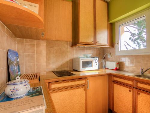 - une cuisine avec des placards en bois et un four micro-ondes dans l'établissement Apartment Les Jardins de la Malouine by Interhome, à Dinard