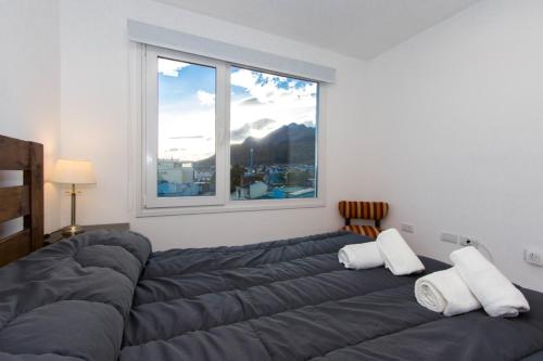 Cama en habitación con ventana grande en Walanika Apartamentos en Ushuaia