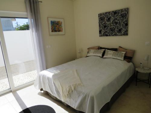 - une chambre avec un lit et une grande fenêtre dans l'établissement Casa Nokleby - Moradia com Piscina Privada e Jardim, à Altura