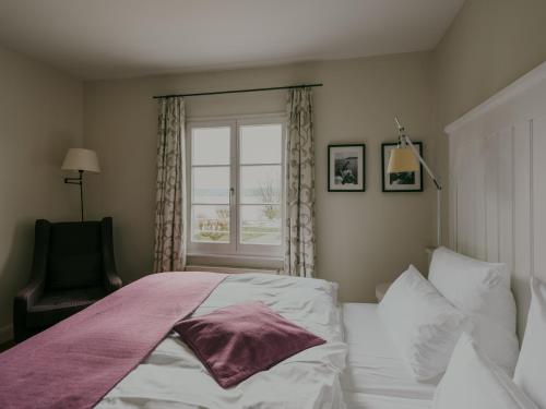 a bedroom with a bed and a window and a chair at Bad Hotel Überlingen in Überlingen