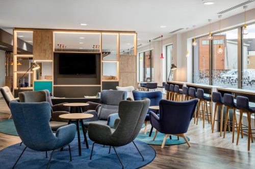 a waiting area with chairs and tables and a bar at Holiday Inn Express Cambridge West - Cambourne by IHG in Cambridge