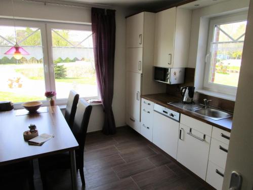 uma cozinha com armários brancos, uma mesa e uma janela em Ferienwohnung Biesterfeld em Bedekaspel