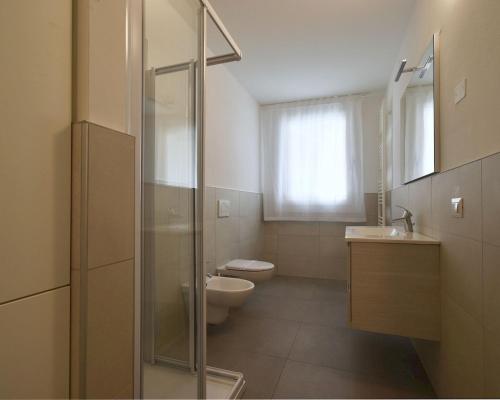 La salle de bains est pourvue de toilettes, d'un lavabo et d'une douche. dans l'établissement Residence Al Molo - Suite Porta del Mar Sea View - Agenzia Cocal, à Caorle