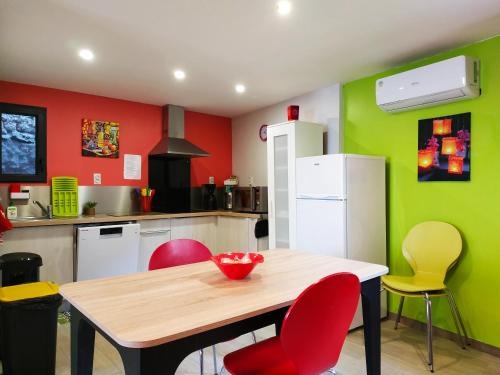 - une cuisine avec une table en bois et des murs rouges et verts dans l'établissement Au Village, à Rennes-le-Château