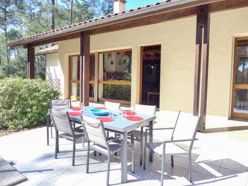 Une table à manger et des chaises sont disponibles sur la terrasse. dans l'établissement Holiday Home Orée des Greens by Interhome, à Le Moutchic