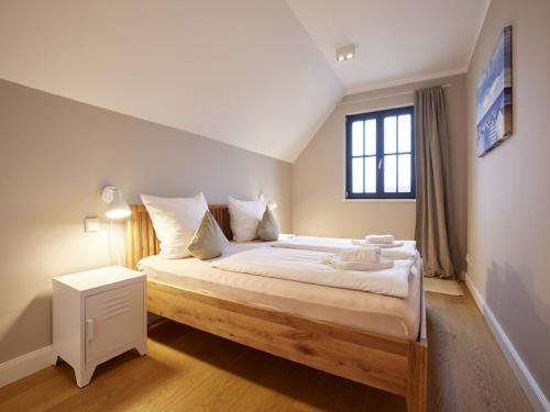 a bedroom with a large bed with a window at Reetland am Meer - Superior Reetdachvilla mit 2 Schlafzimmern F02 in Dranske