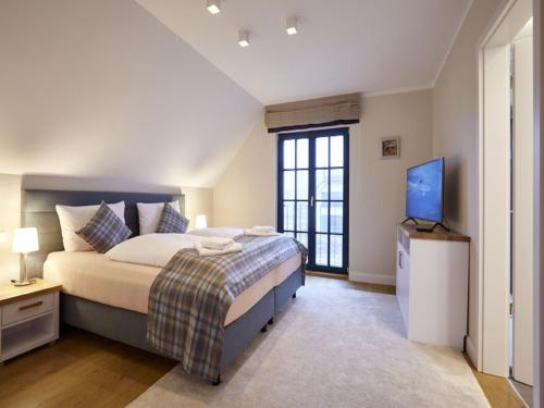 德蘭斯克的住宿－Reetland am Meer - Luxus Reetdachvilla mit 3 Schlafzimmern, Sauna und Kamin F15，一间卧室配有一张床和一台电视