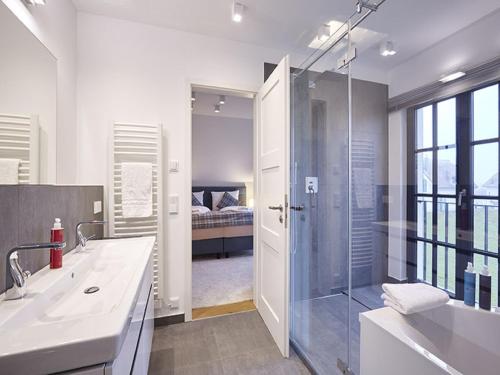 a bathroom with a shower and a sink and a tub at Reetland am Meer - Luxus Reetdachvilla mit 3 Schlafzimmern, Sauna und Kamin F15 in Dranske