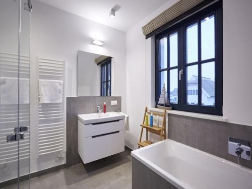 baño con bañera, lavabo y ventana en Reetland am Meer - Superior Reetdachvilla mit 2 Schlafzimmern F16, en Dranske