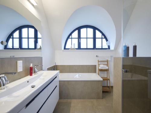 baño con bañera y lavamanos y 2 ventanas en Reetland am Meer - Premium Reetdachvilla mit 3 Schlafzimmern, Sauna und Kamin F14, en Dranske