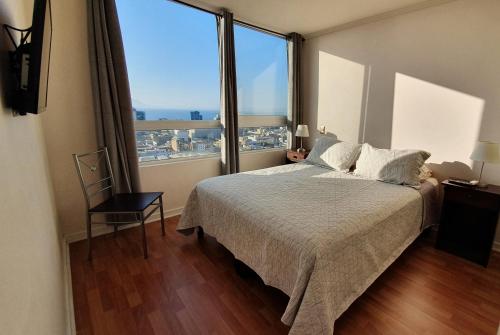 a bedroom with a large bed and a large window at Antofagasta Sunset - Amplio Departamento con Home Office y Vista Mar in Antofagasta