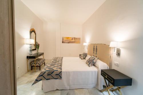 a white bedroom with a bed and a table at Arco Macarena Lofts in Seville