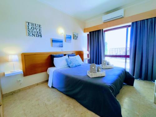 - une chambre avec un lit bleu et des serviettes dans l'établissement Seaview Apartment Clube Praia Mar, à Portimão